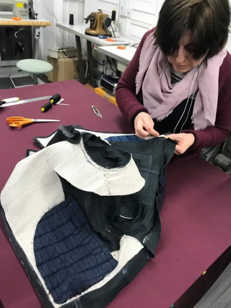 Artisane de l’atelier assemblant à la main une pièce en crocodile bleu marine